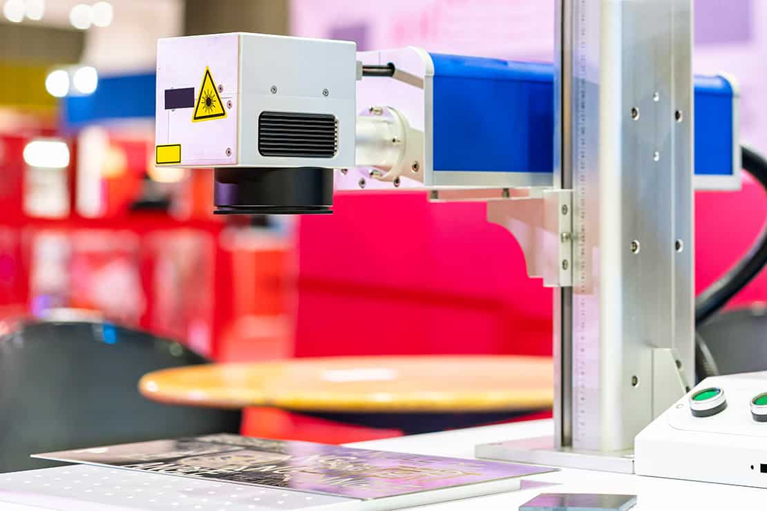 A MOPA fibre laser galvo head positioned over an engraving surface